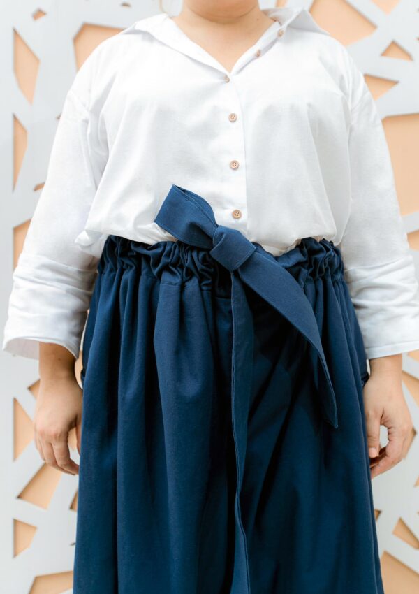Plus size woman wearing dark blue cotton trousers and white shirt