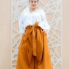 Plus size woman wearing oversized orange trousers made from sustainable fabric